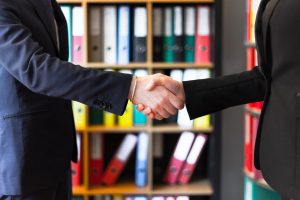 Two people shaking hands in office